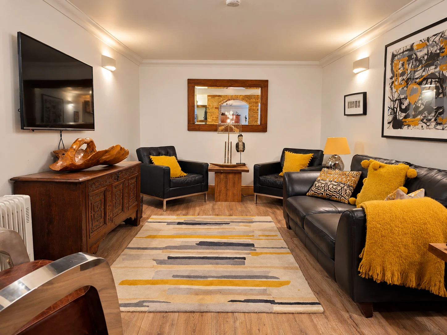 The lower-ground-floor sitting room with black leather seating and mustard accents
