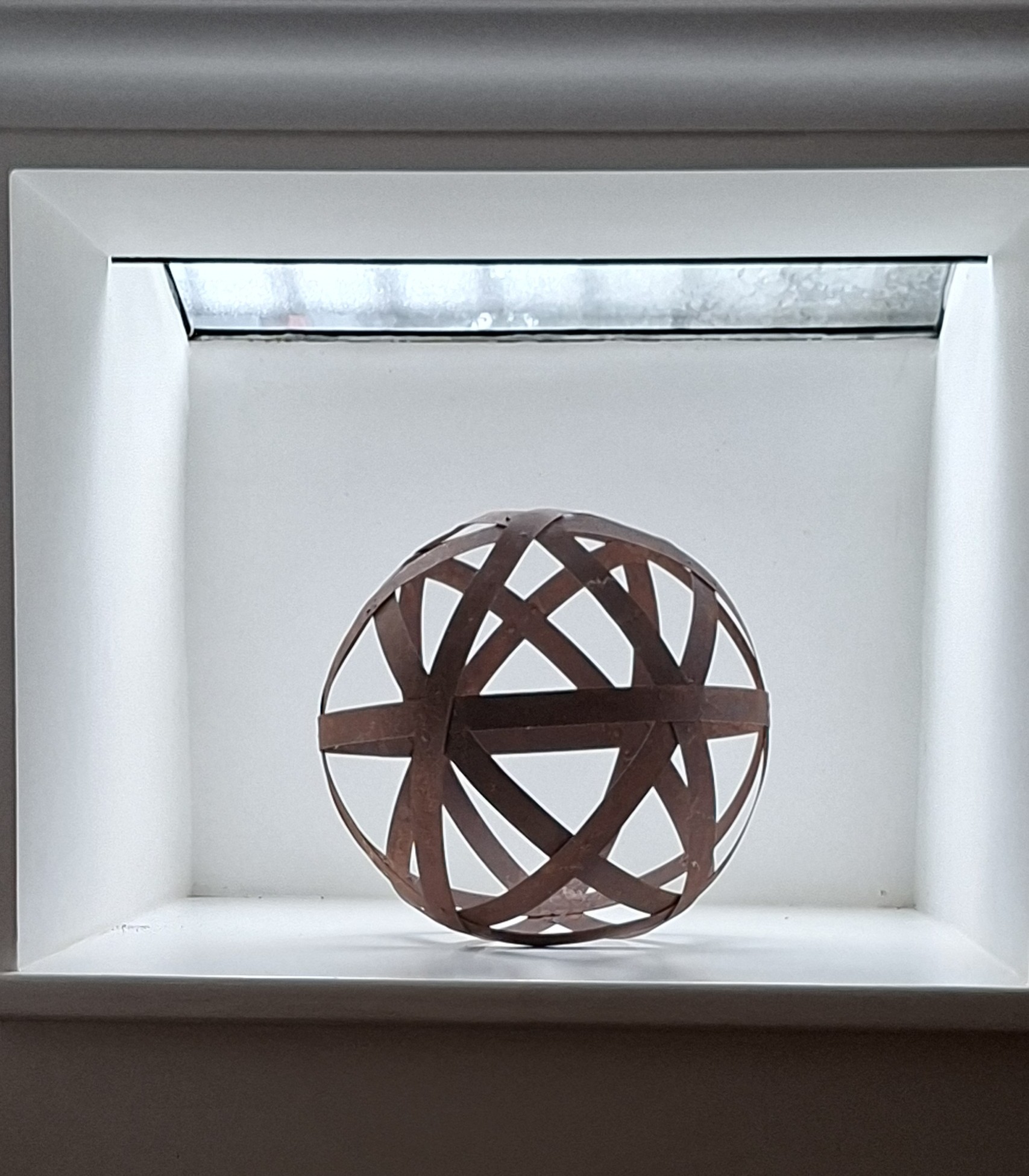 Sculptural metal sphere displayed in a softly lit niche at Havisham House